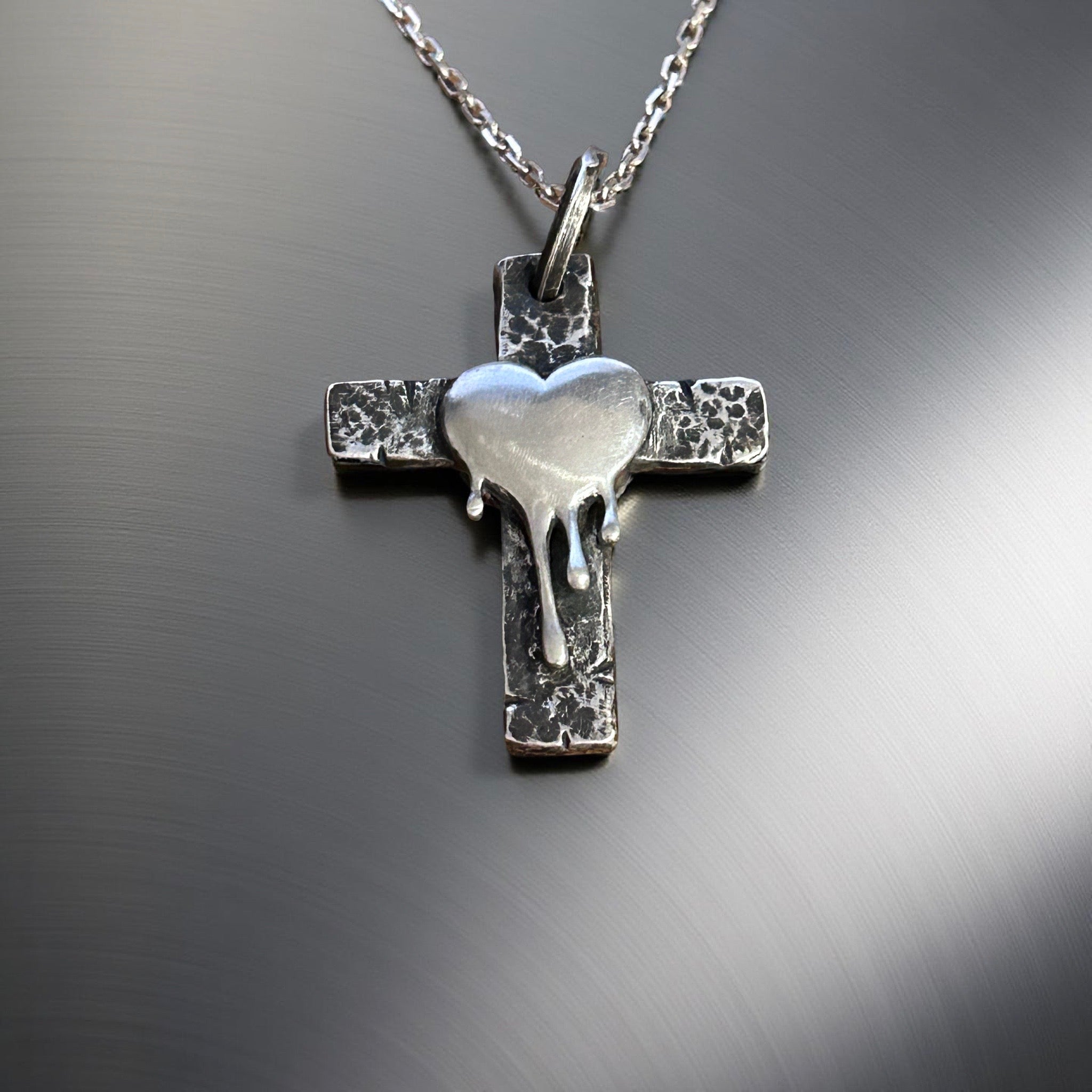 Handcrafted sterling silver cross pendant with melting heart design.