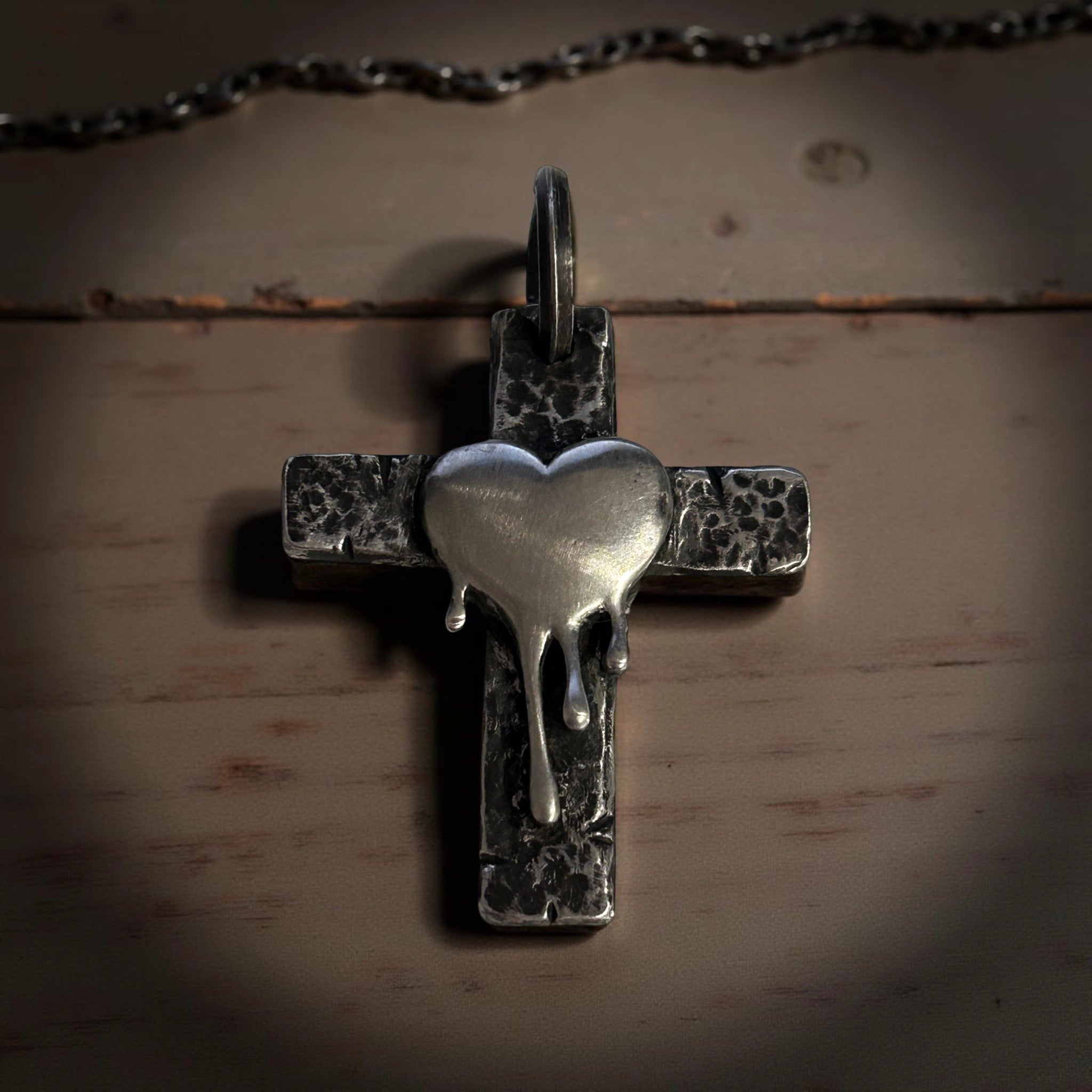 Handcrafted sterling silver cross pendant with melting heart design.