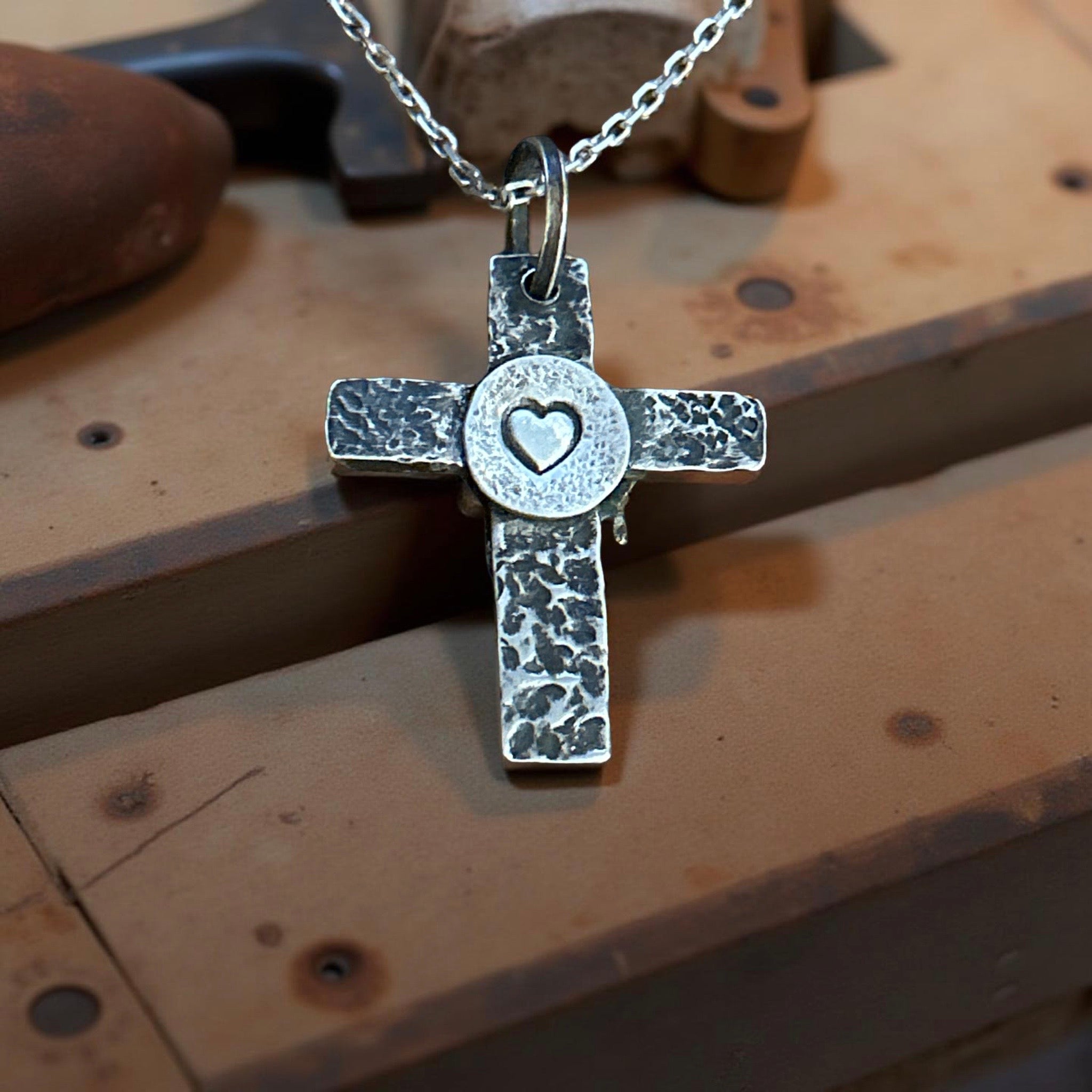 Handcrafted sterling silver cross pendant with melting heart design.