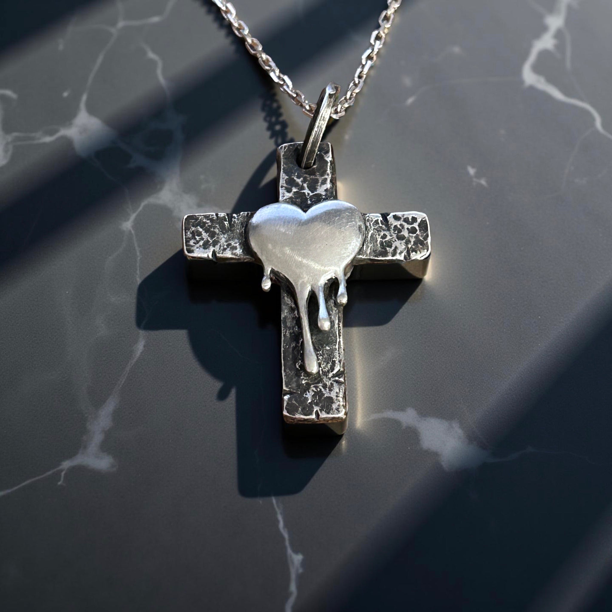 Handcrafted sterling silver cross pendant with melting heart design.