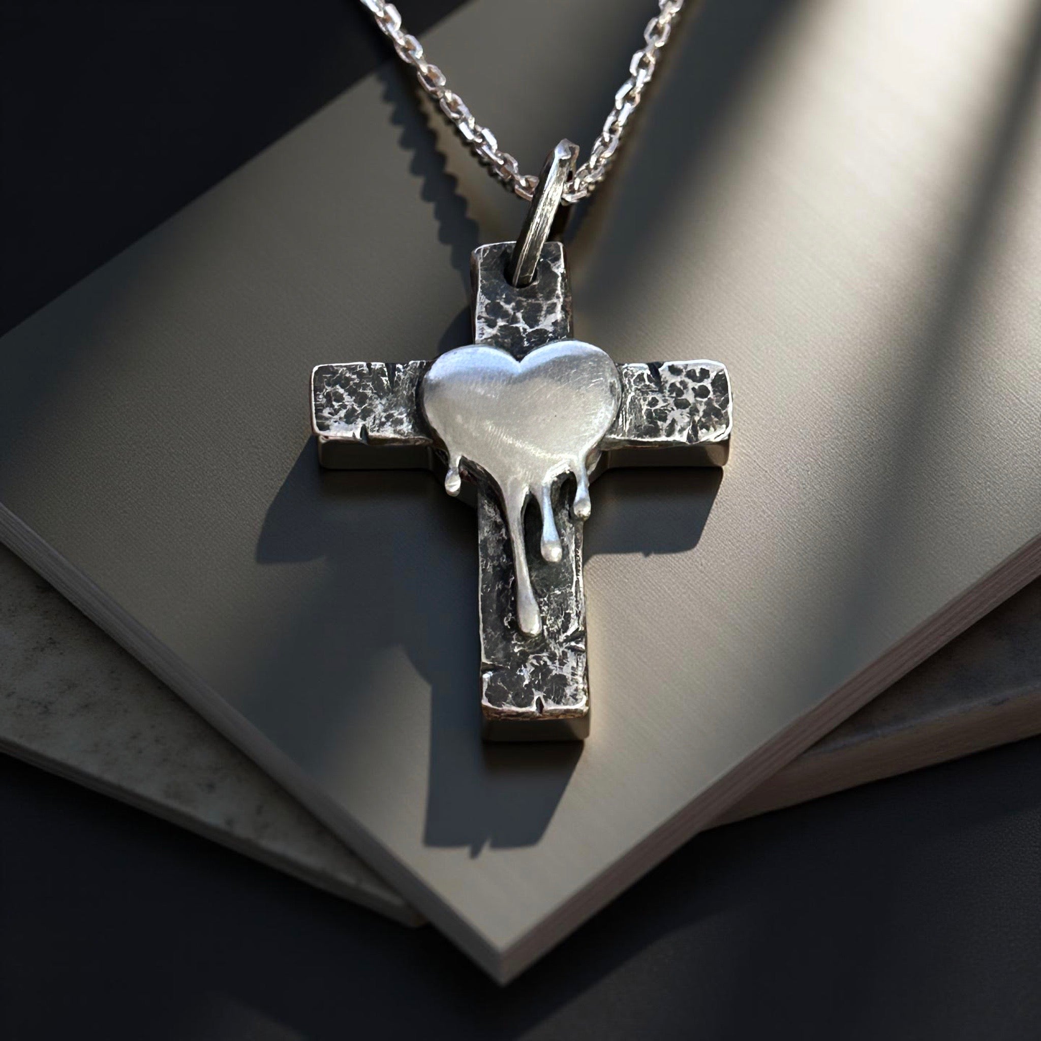 Handcrafted sterling silver cross pendant with melting heart design.