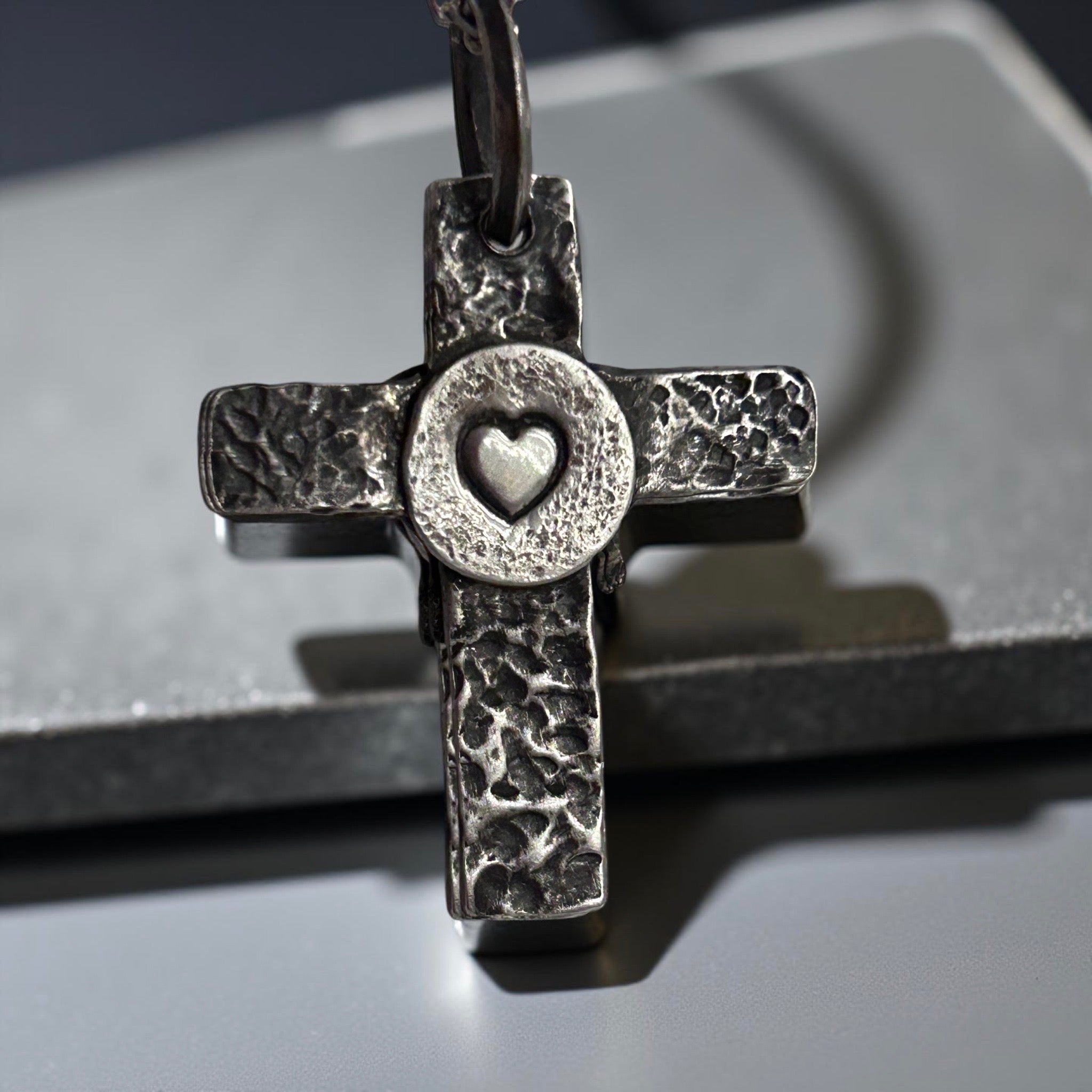 Handcrafted sterling silver cross pendant with melting heart design.