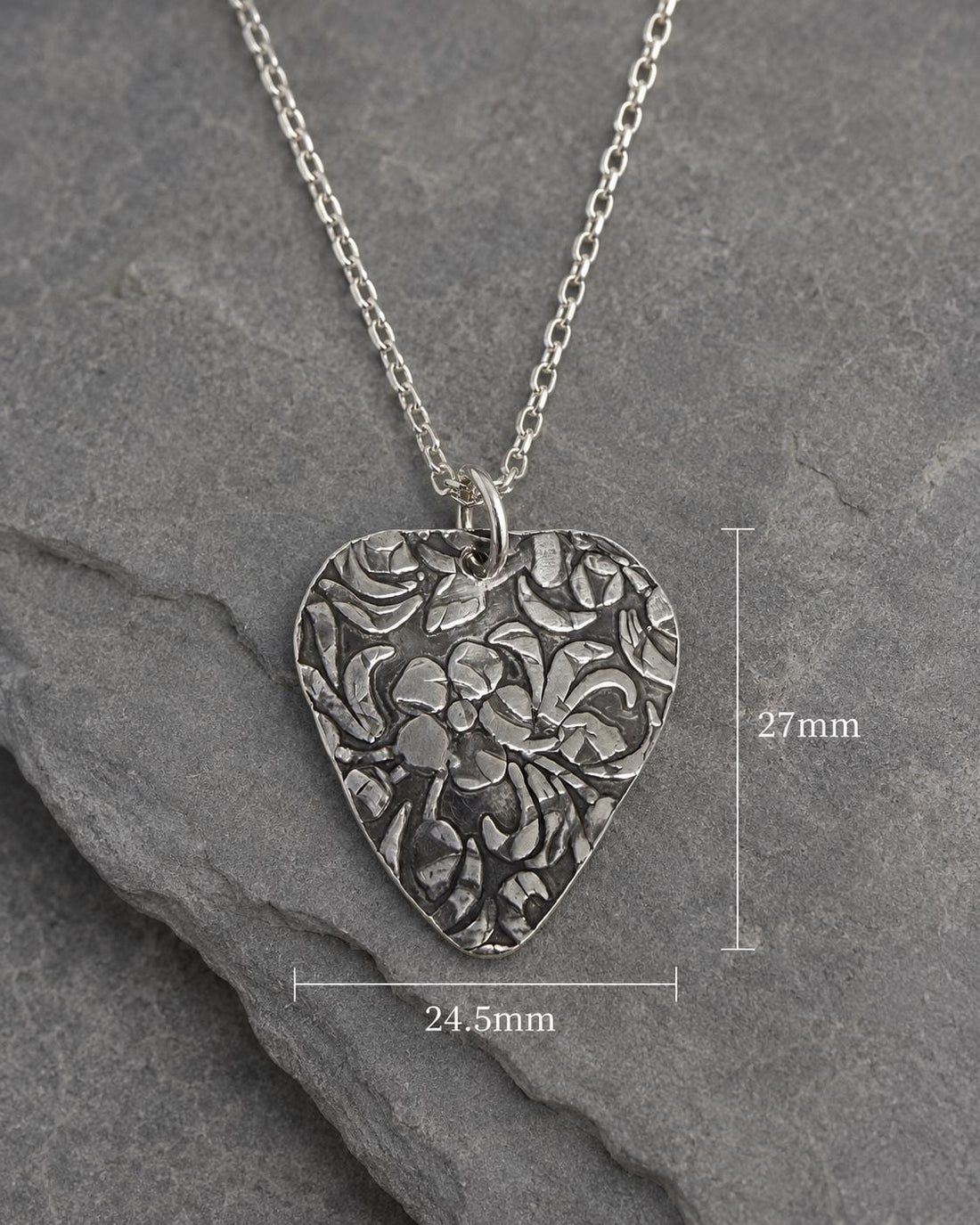 Silver guitar pick pendant with floral engraving, music jewelry accessory by JJewelryArt, displayed on a neutral background.